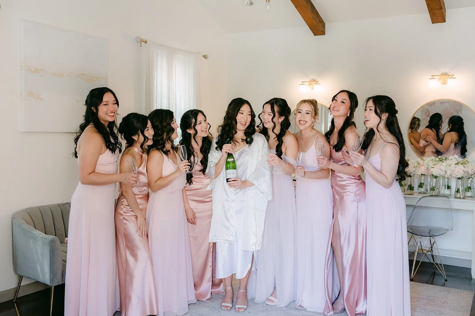Kelli in her robe surrounded by her bridesmaids in blush dresses in the Los Robles Greens Bridal Suite