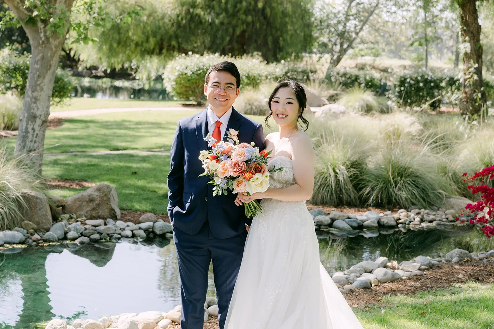 Couple standing beside the pond with the bridal bouquet