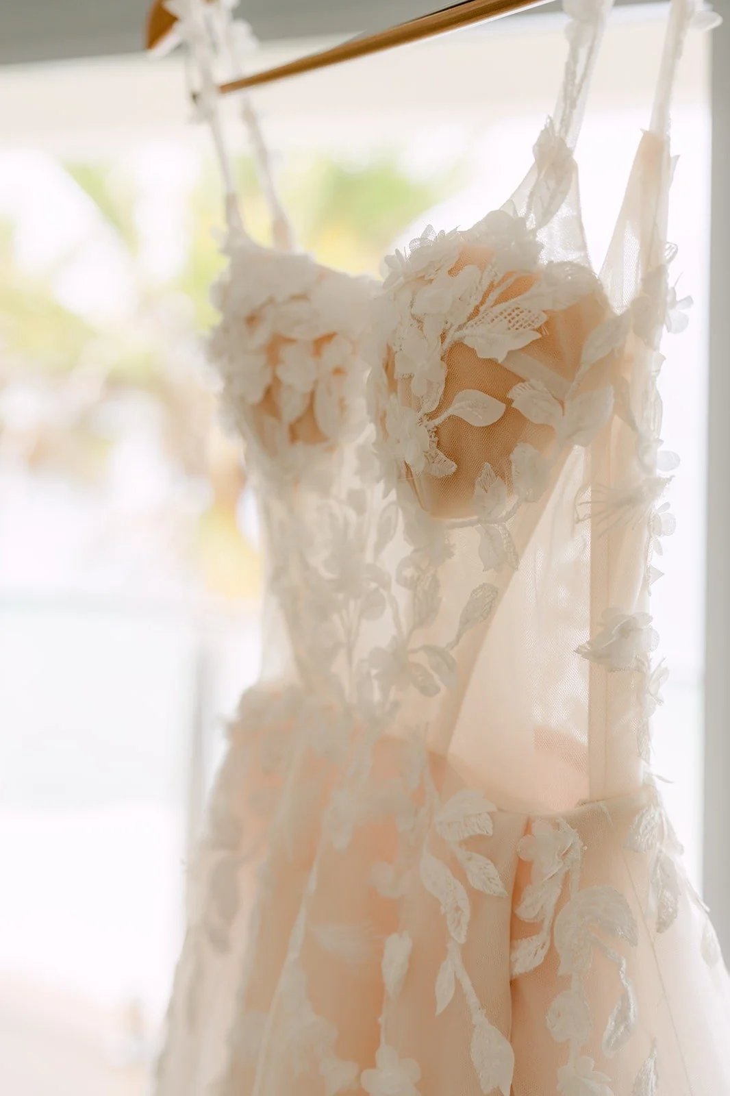 Close view of the lace flowers on Kylie's gown as it hangs by the window