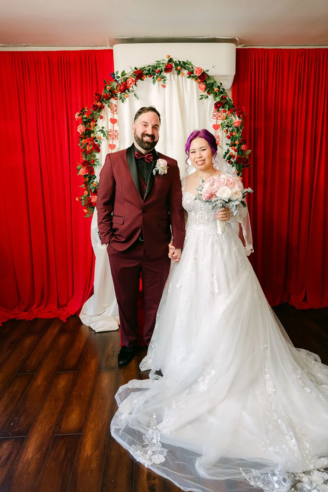 Vanessa and Ryan under the rose arch with her long train.