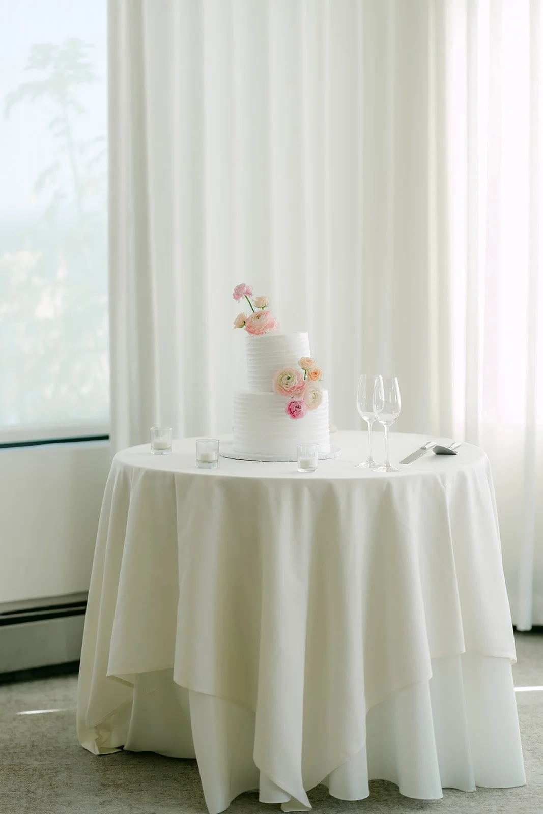 Wedding cake on a draped table by the window