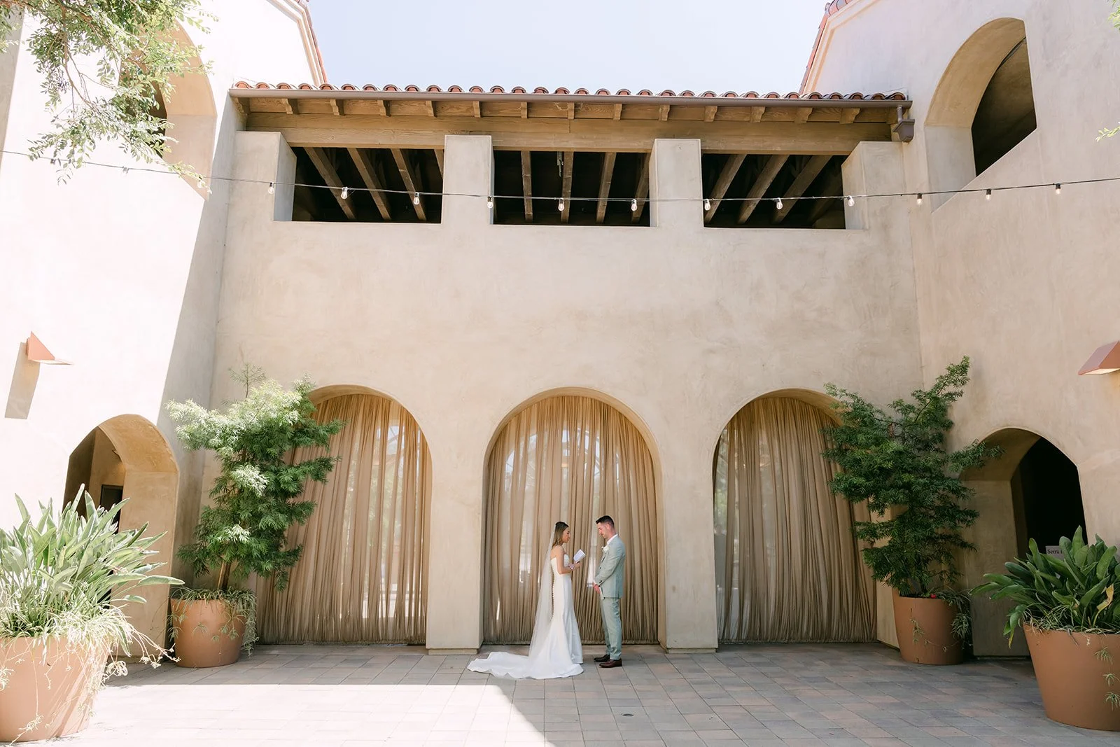 Wide view of the couple in the Serra Plaza courtyard beneath the loggia