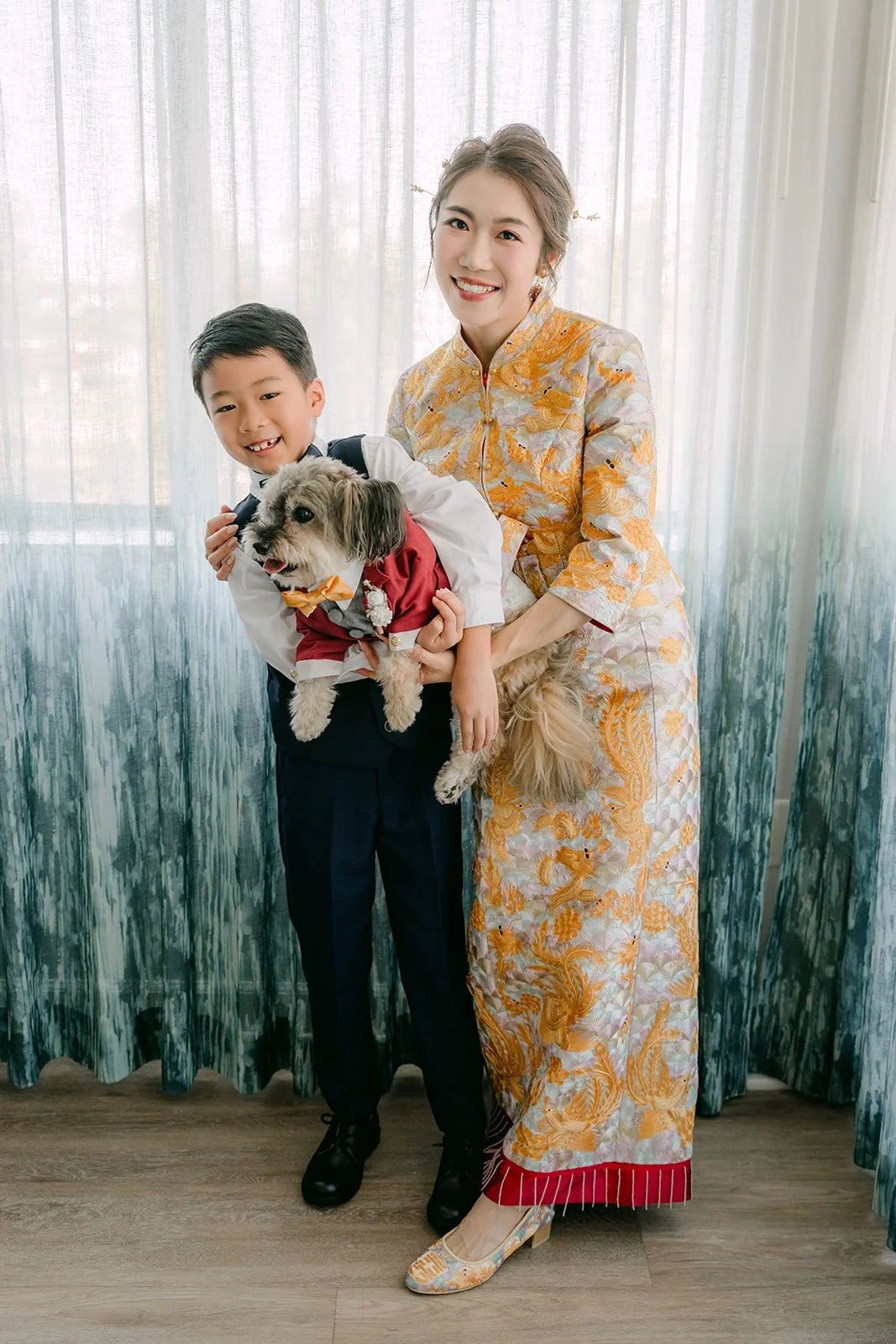 Christie in her qun kwa holding Izzo next to a young nephew in a vest.