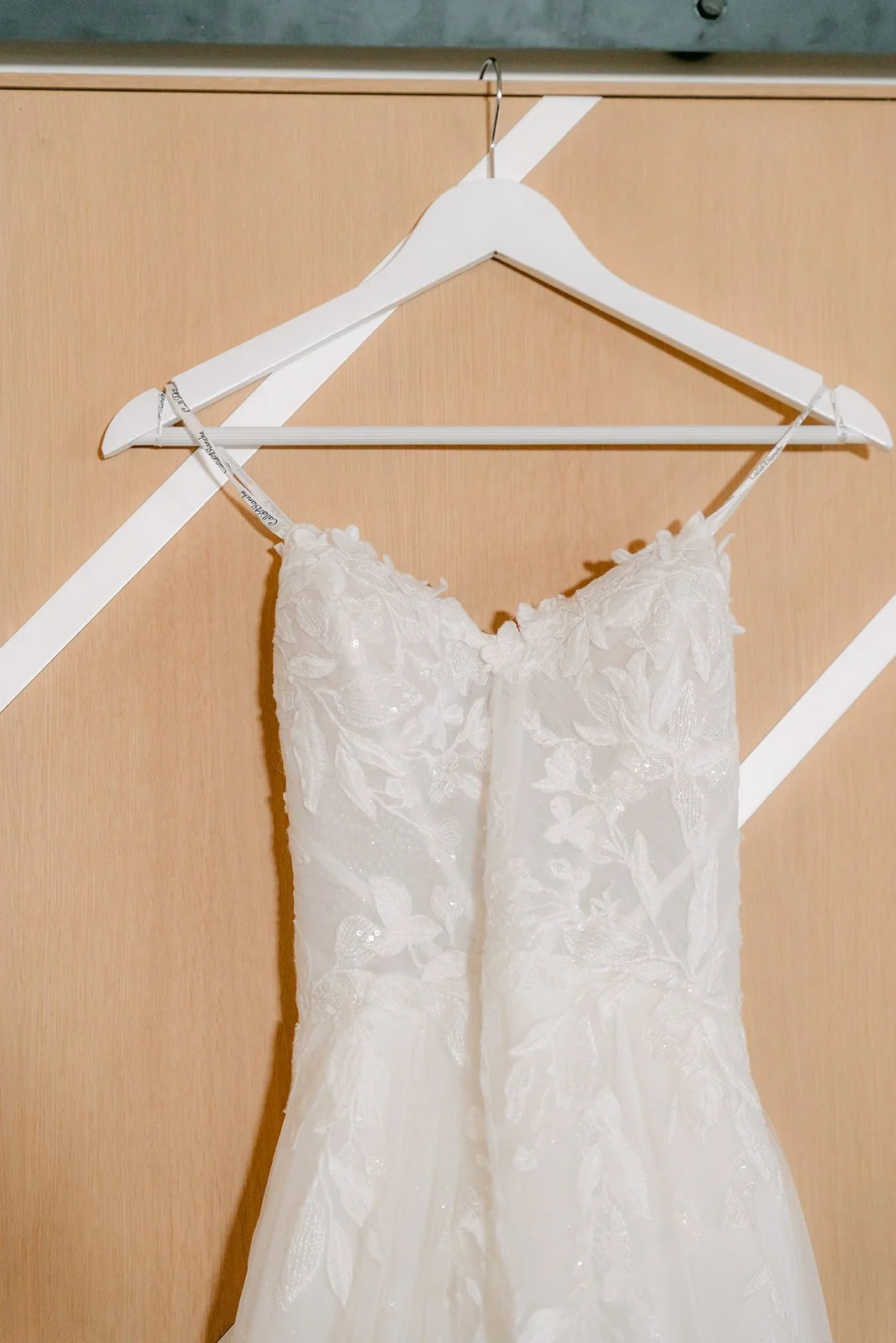 Lace wedding gown hanging on a wood barn door at The Colony House