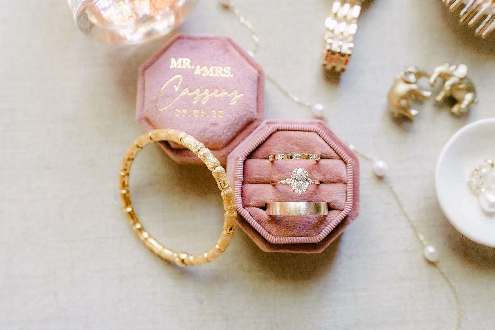 Joanne's engagement ring in a pink velvet ring box beside a gold bracelet and earrings