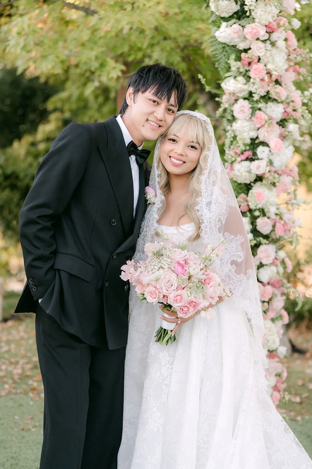 Konitha and Job smiling beside blush and white florals