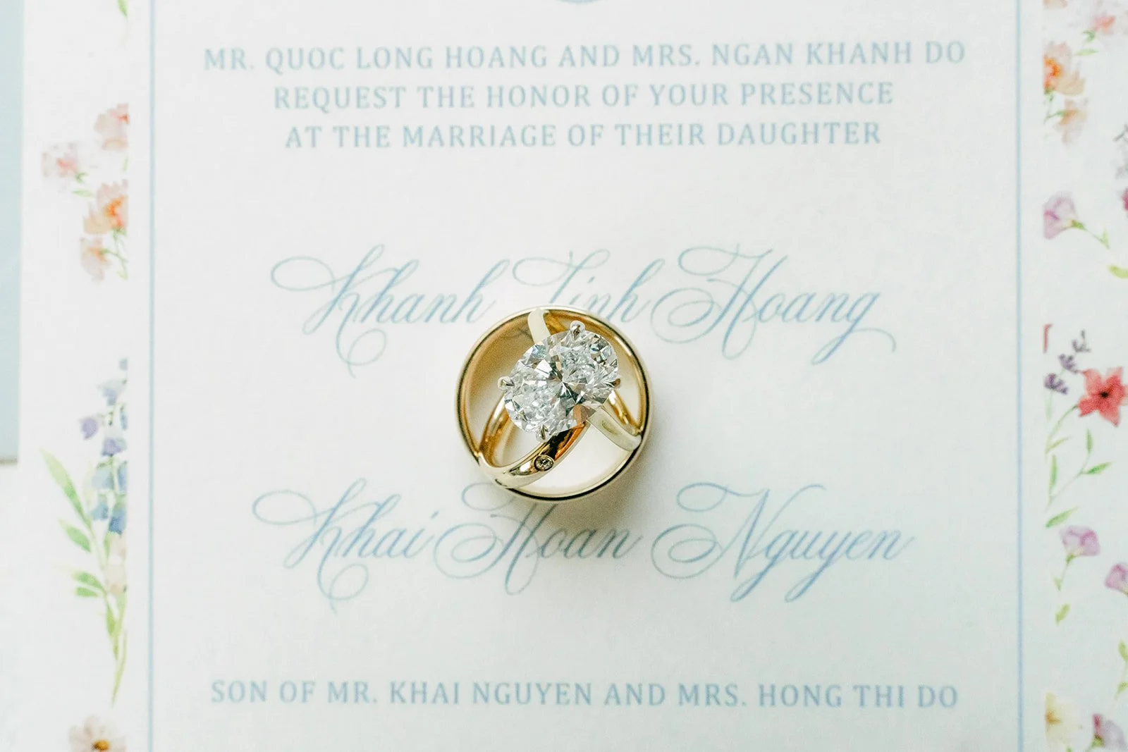 Wedding rings resting on Linh and Hoan's watercolor wedding invitation
