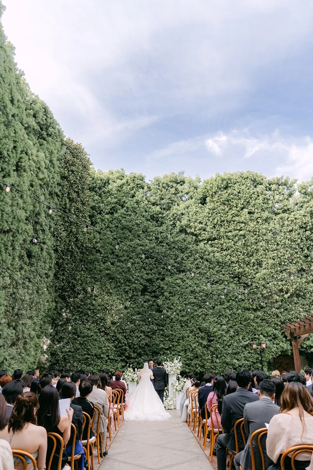 A wide view of the ceremony in the hedge walled courtyard at Franciscan Gardens