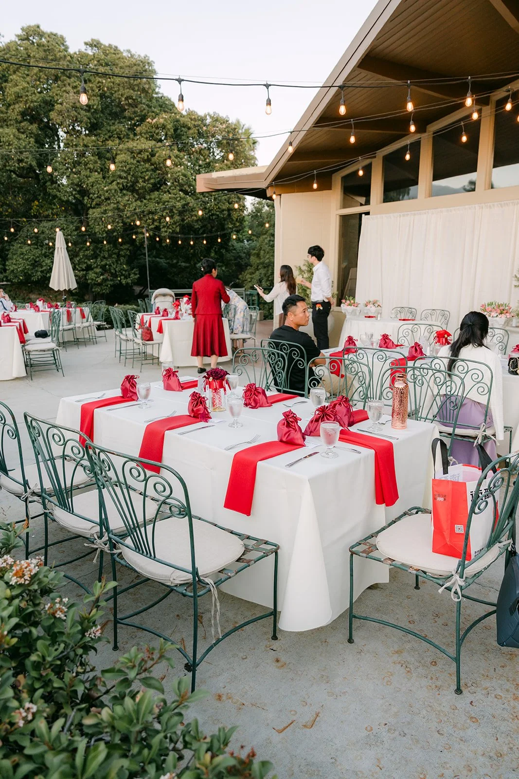 Reception tables on the Peacock Cafe patio with red runners and string lights.