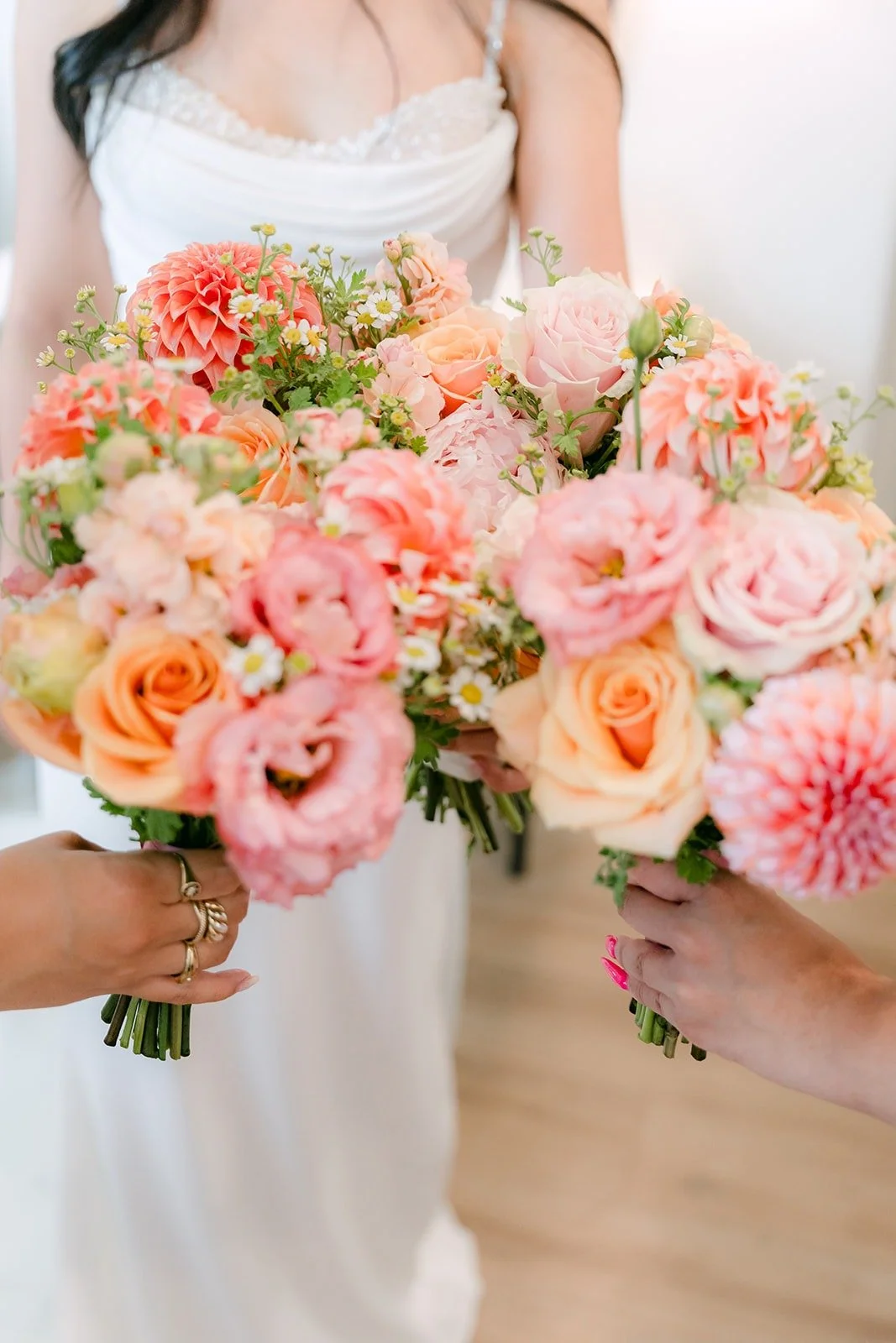 Stephanie's bouquet of peach and pink roses and dahlias held against her white gown