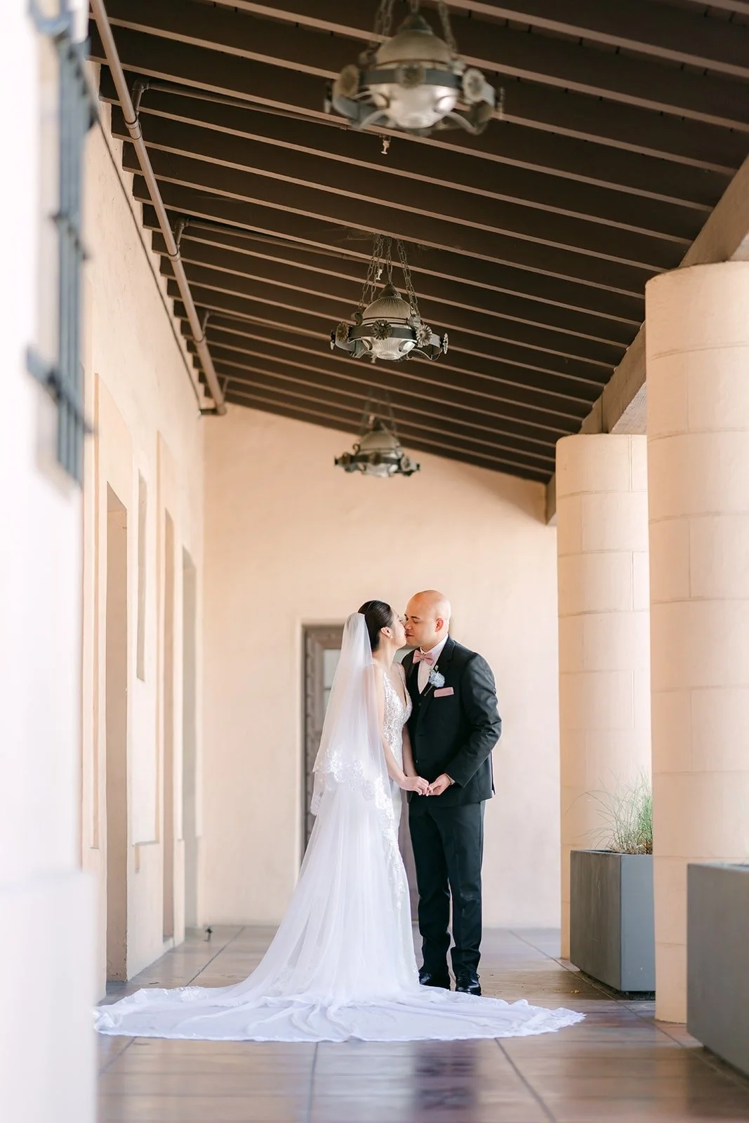 Elisa and Brandon under the wood beamed ceiling of the covered walkway