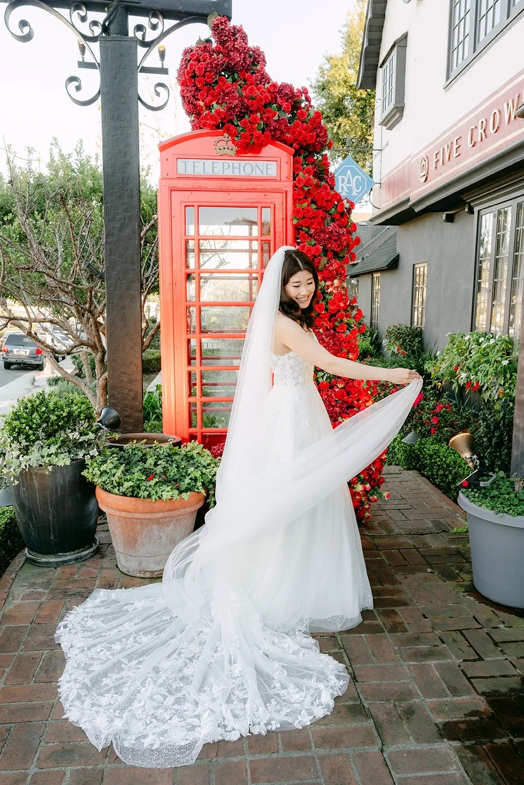 Valerie with her veil and train spread in front of the red phone booth at Five Crowns