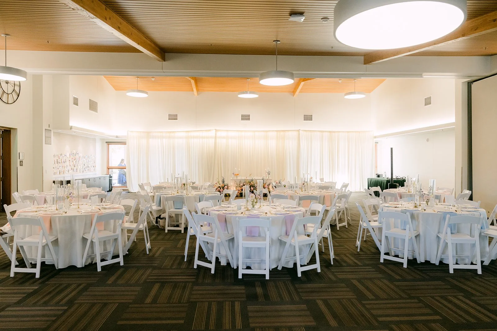 The reception room at Quail Hill Community Center set with round tables and white drapes.