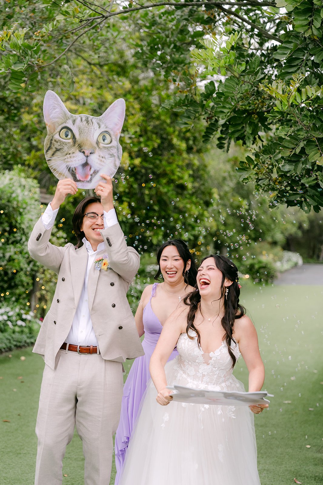 Mike holding a cat face cutout over his head as Kat laughs, photographed by One and Only Production