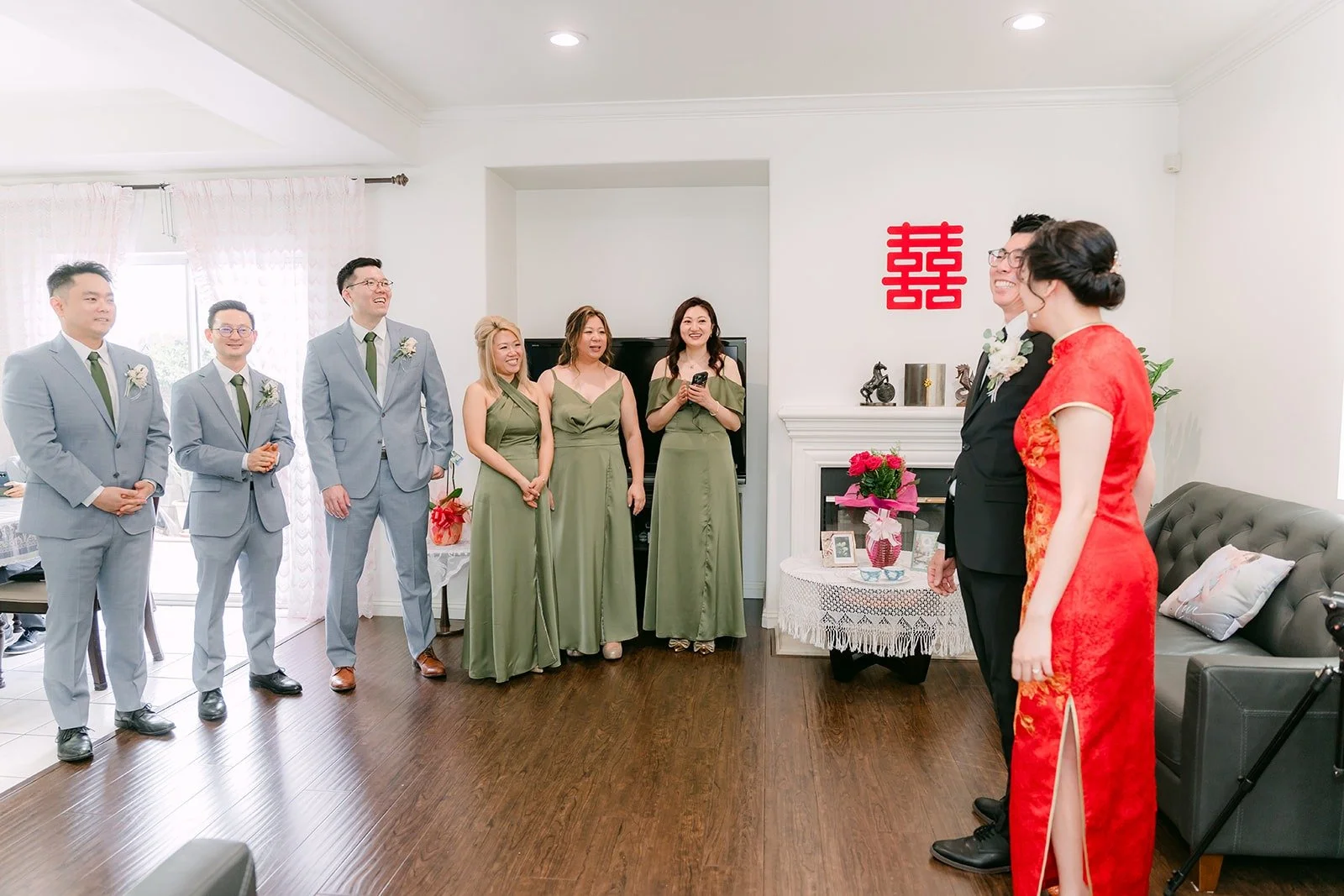 The groomsmen and bridesmaids gathered in the living room under the double happiness sign