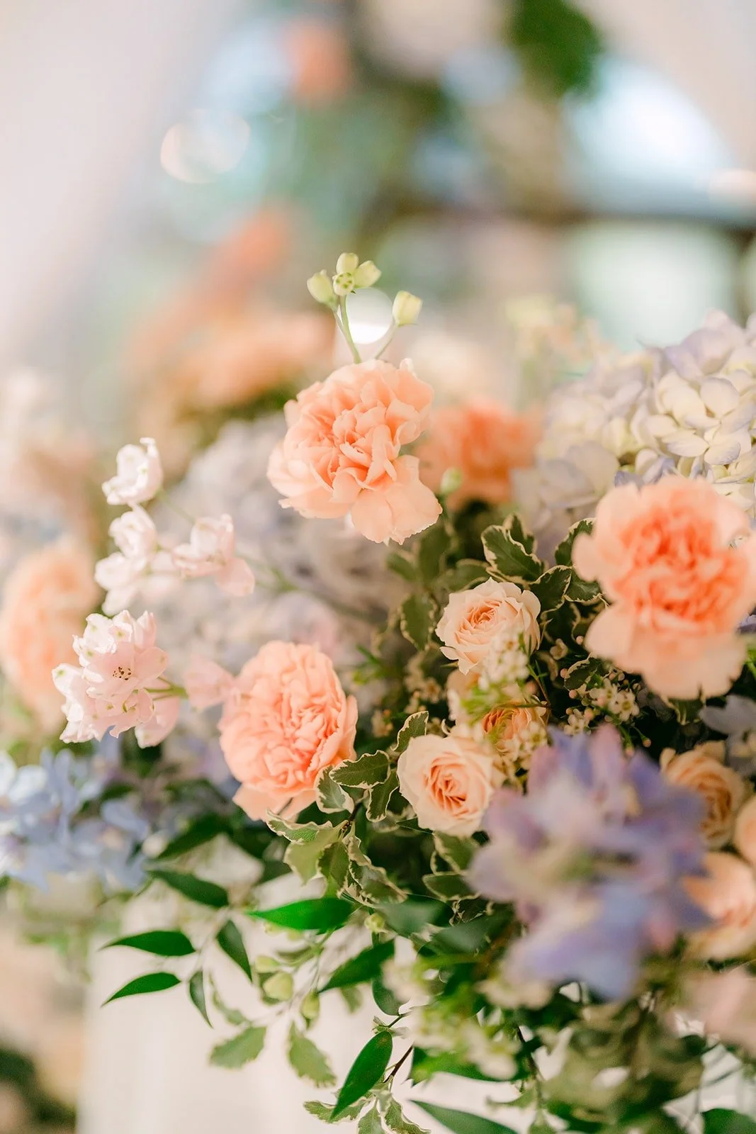 Close up of peach roses and blue delphinium on the reception tables, photographed by One and Only Production