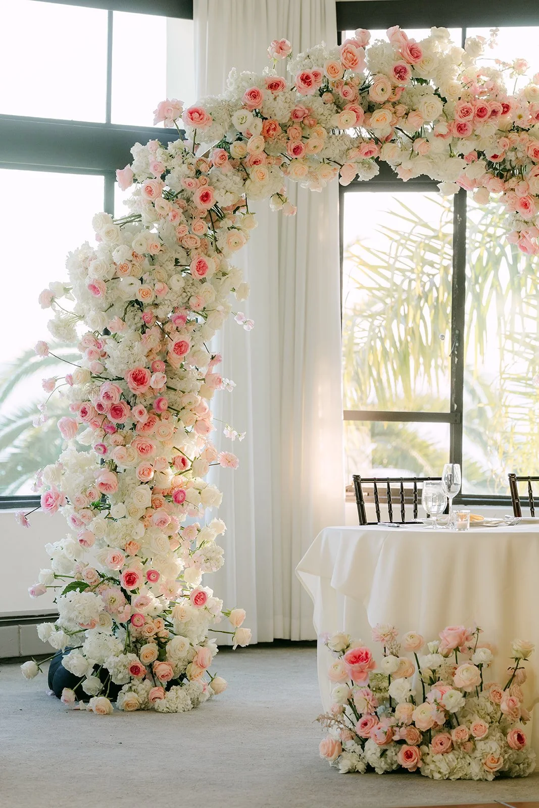 Floral arch framing the sweetheart table by the ocean view windows