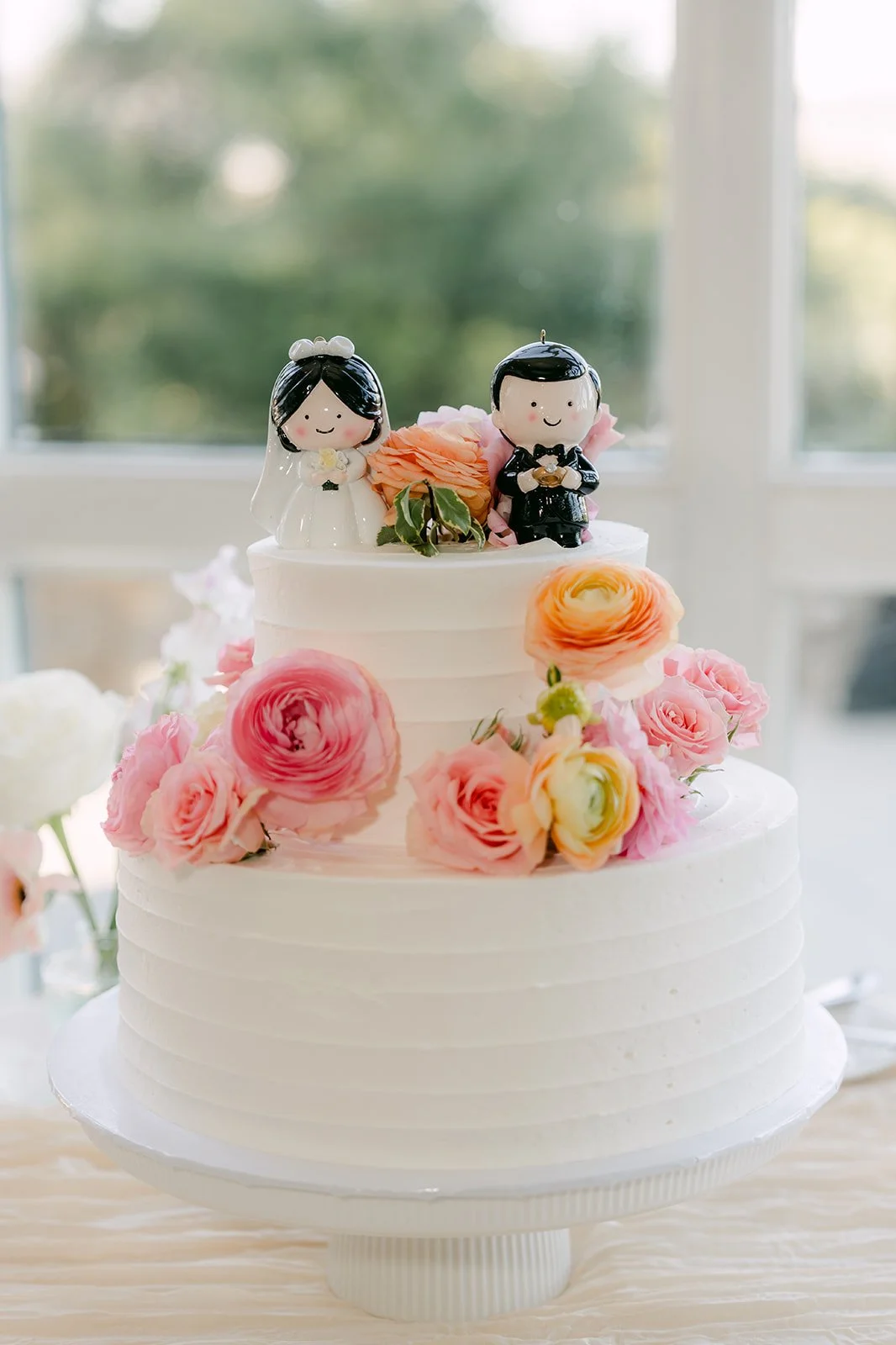 The white wedding cake topped with pink roses