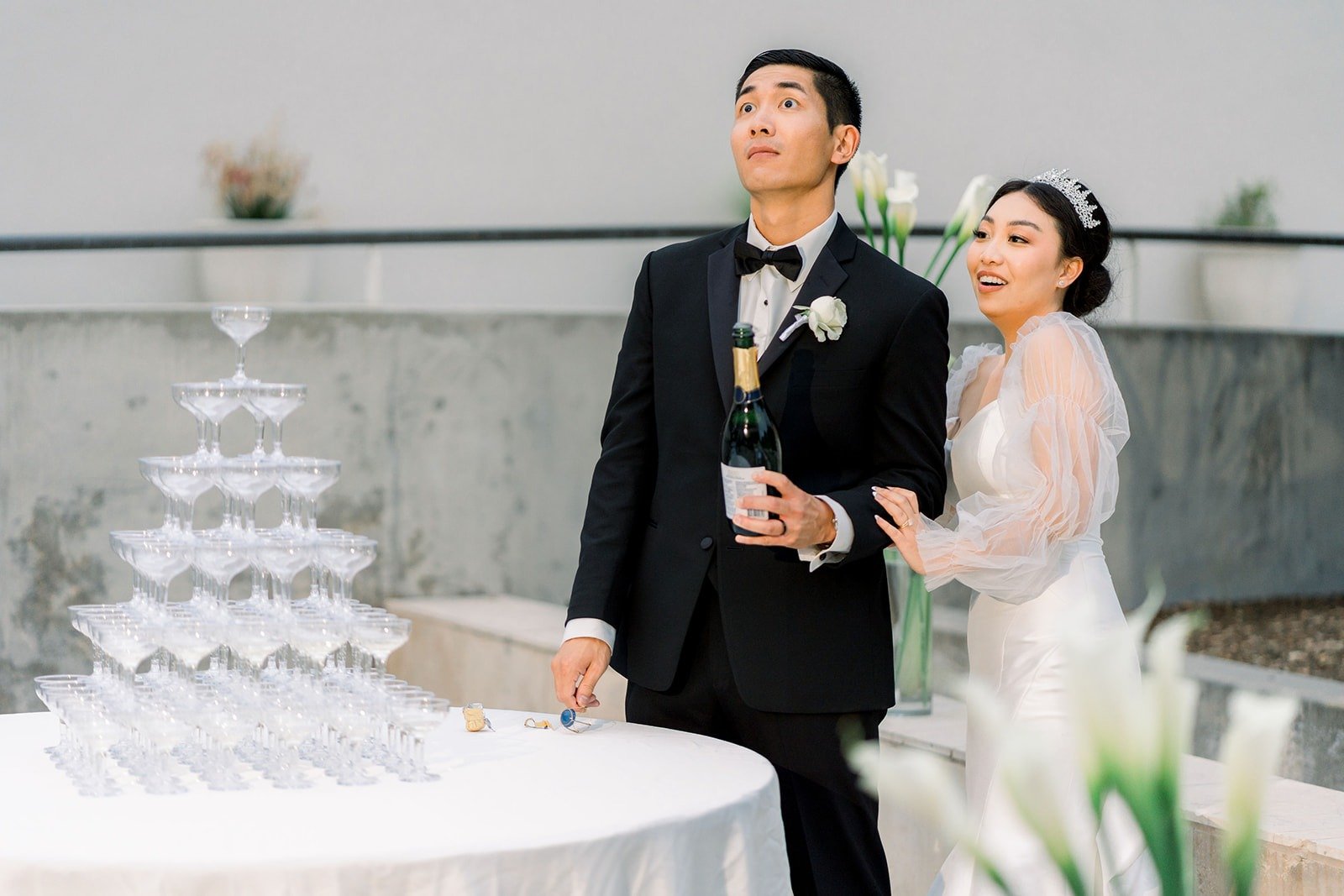 Steven and Jacinda laugh beside the champagne tower