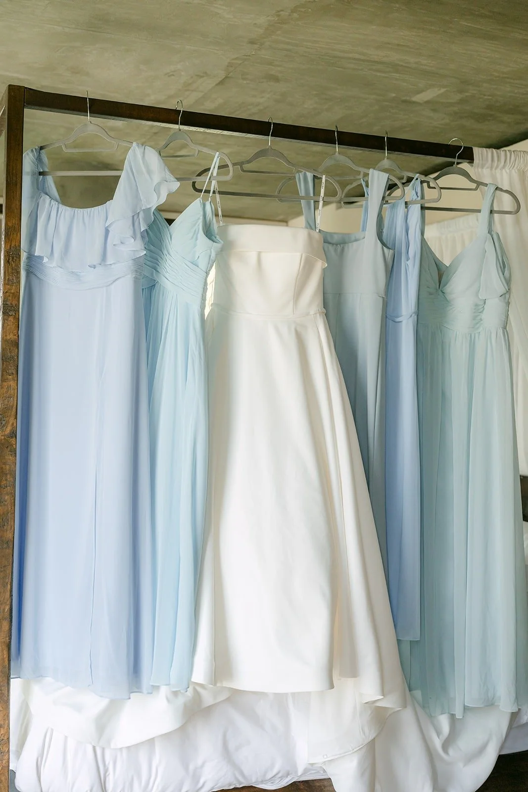 Bridesmaid dresses in shades of dusty blue hanging in the suite
