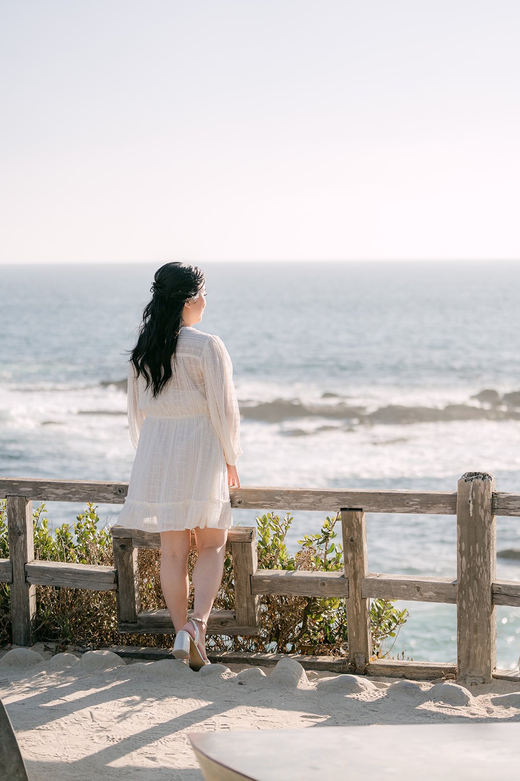 Constance in a white dress at the bluff railing.