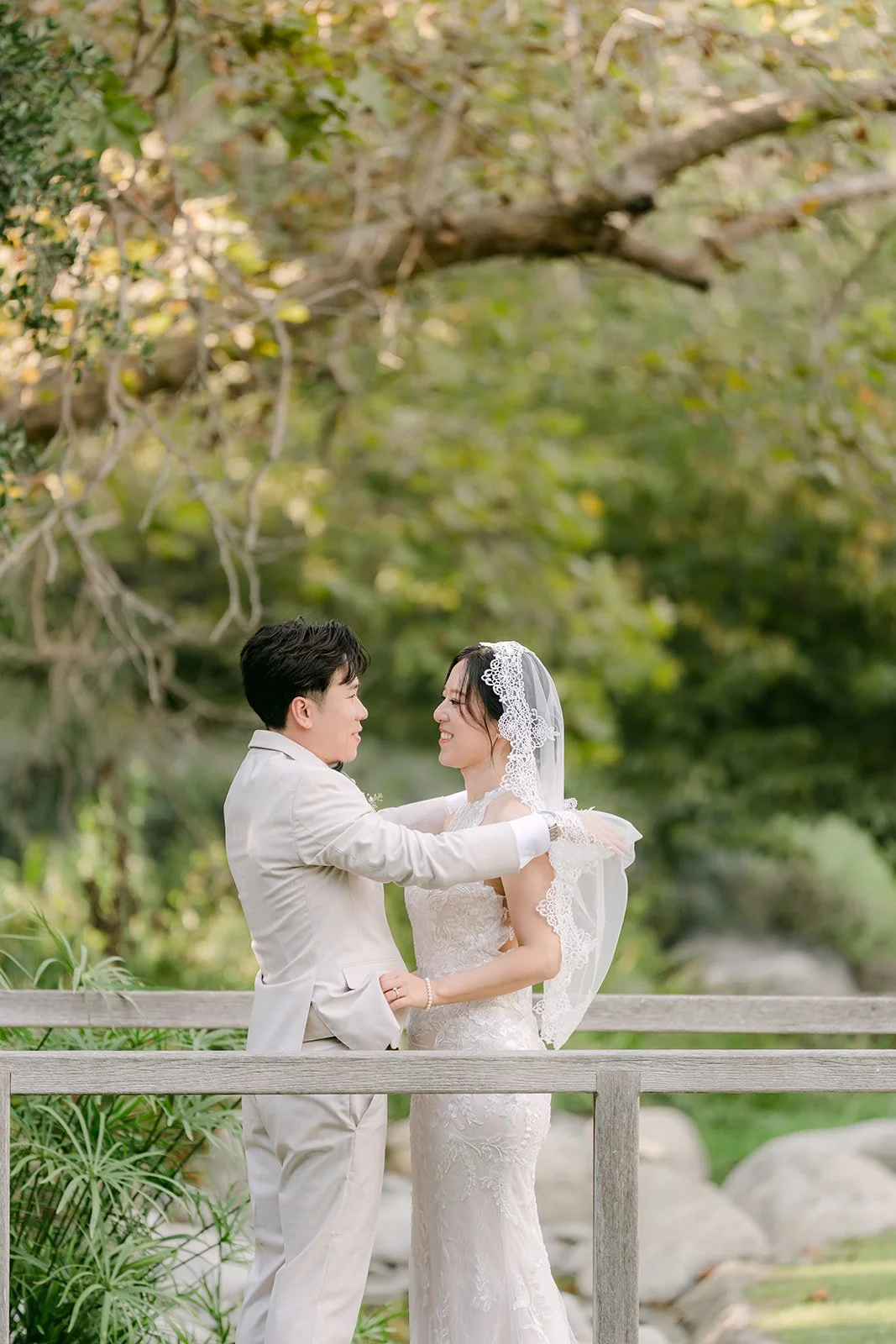 Wen holding Elaine on the wooden bridge under an oak tree.
