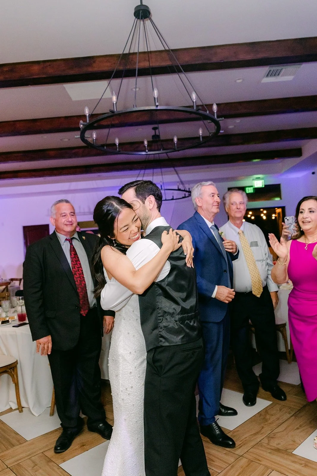 Stephanie and Kevin hugging on the dance floor under the chandelier