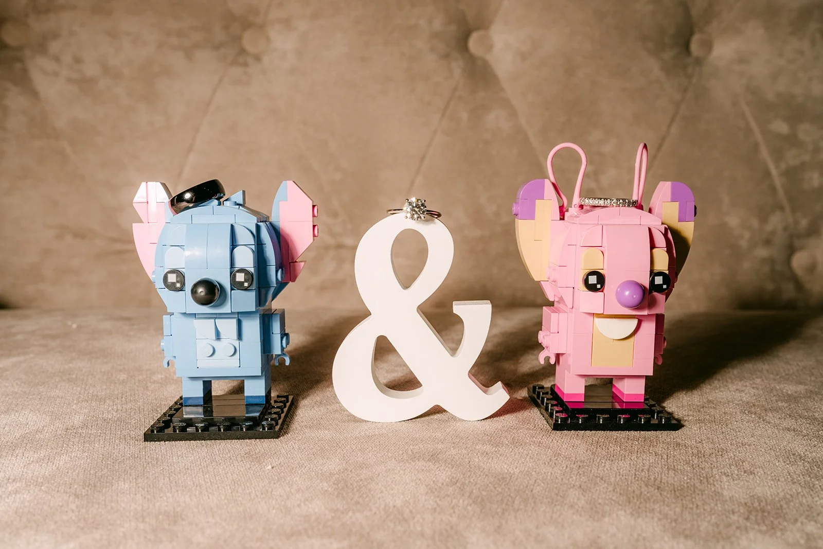 Stitch and Angel toy figures with a white ampersand, photographed by One and Only Production.