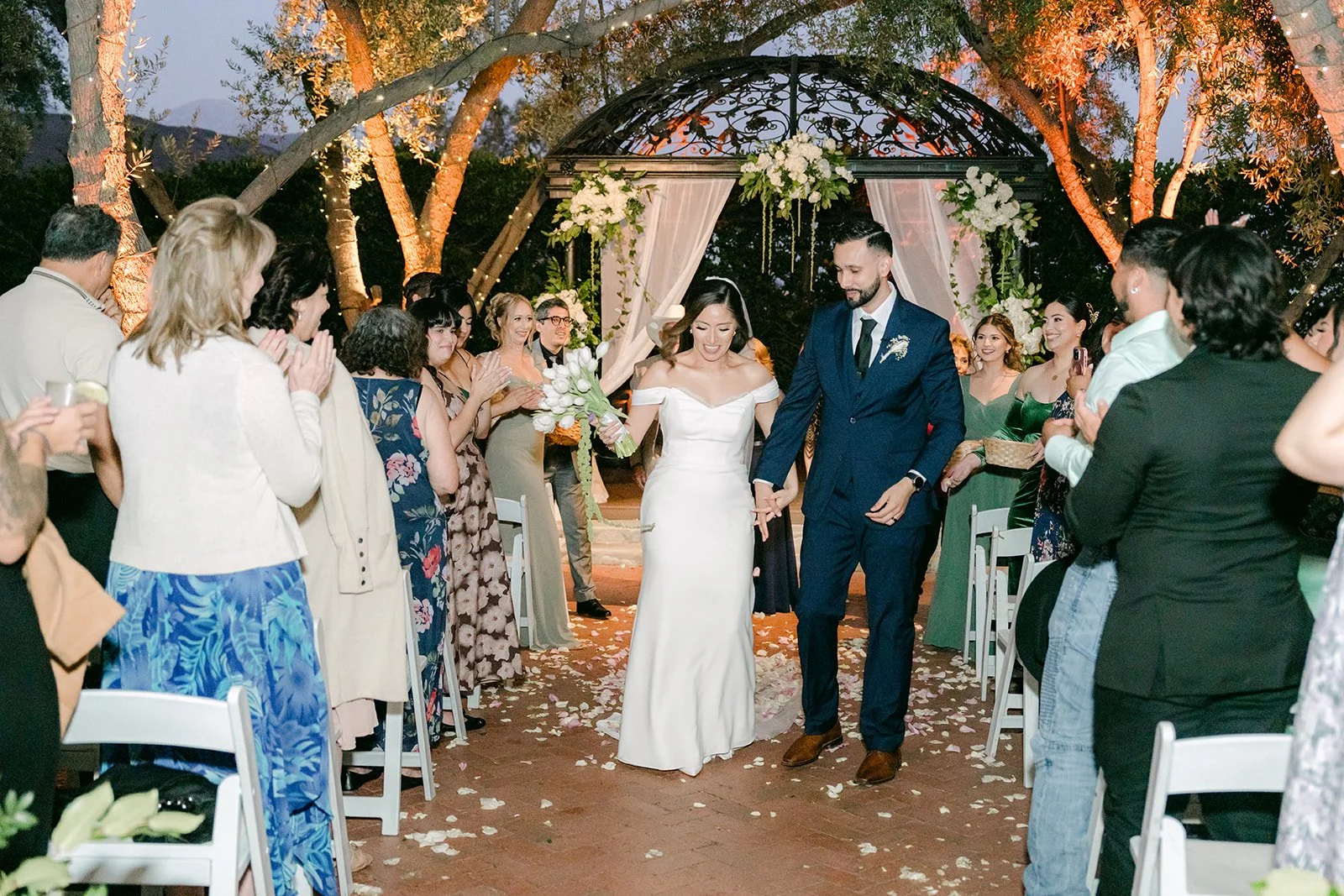 Guests clapping as Mariana and Danny reach the end of the aisle