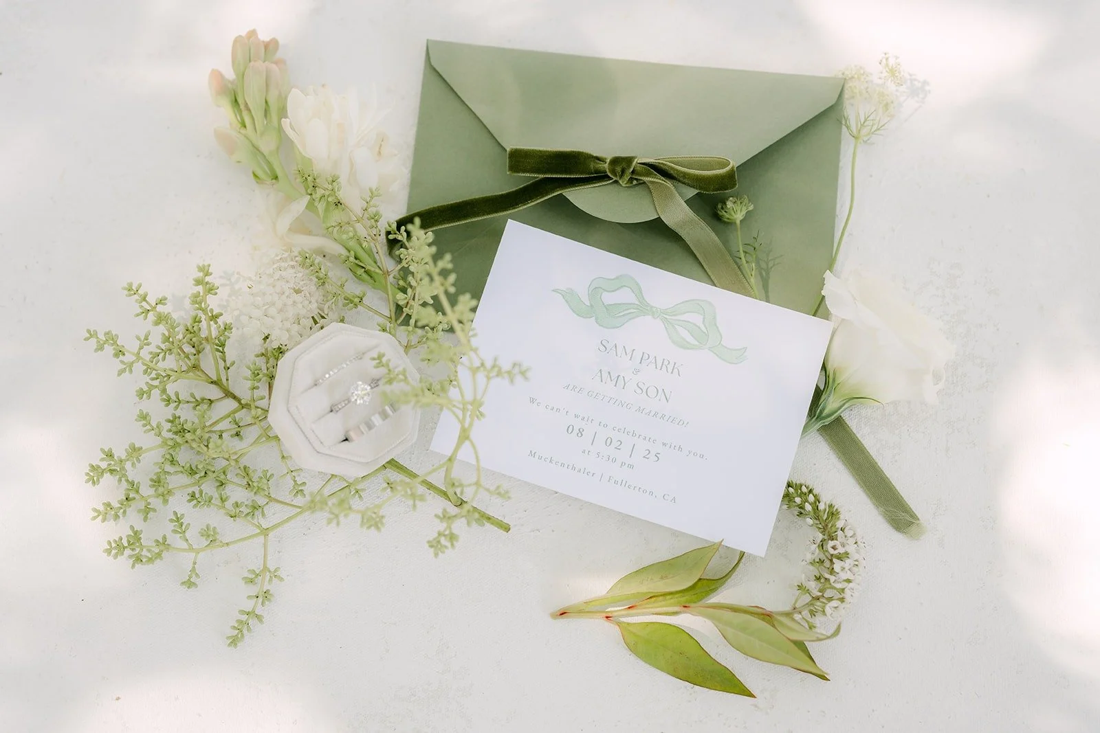 Invitation and sage envelope styled with greenery