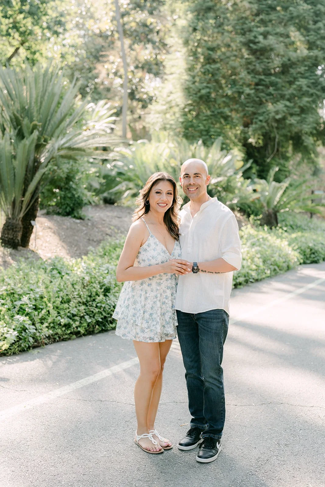 Francesca and Daniel stand together among tropical plants along the garden path.