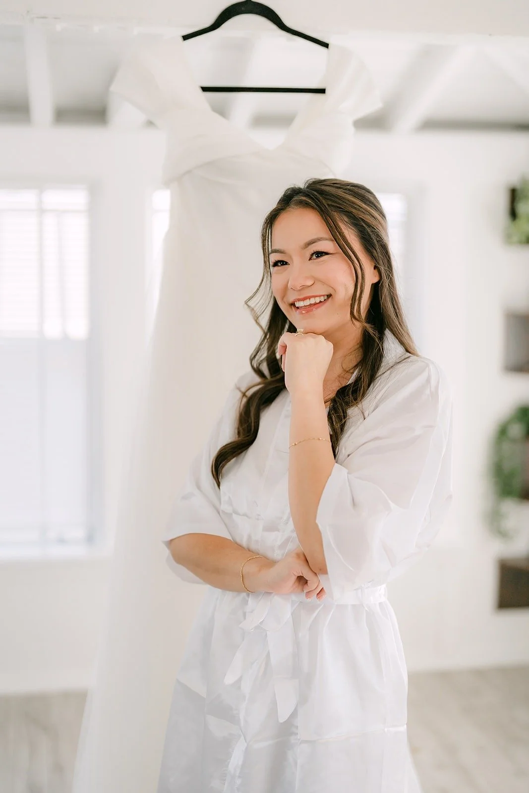 Jadee in a white robe in front of her hanging gown