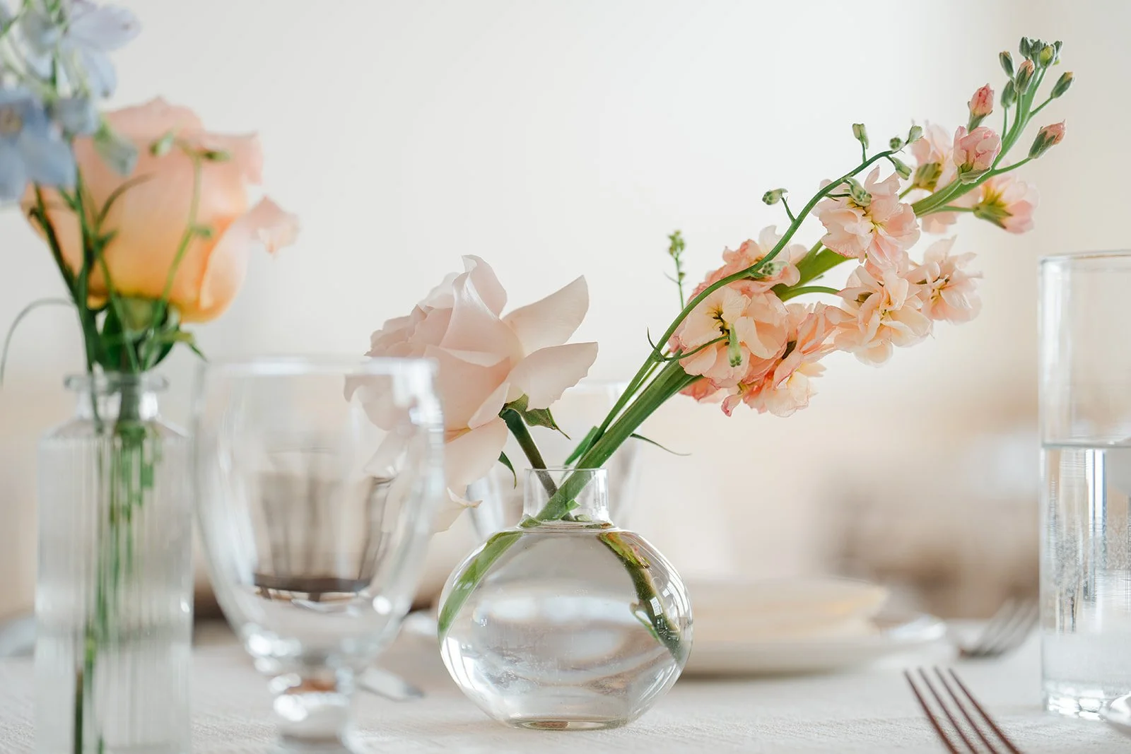 Bud vases with peach and pink blooms on the reception tables