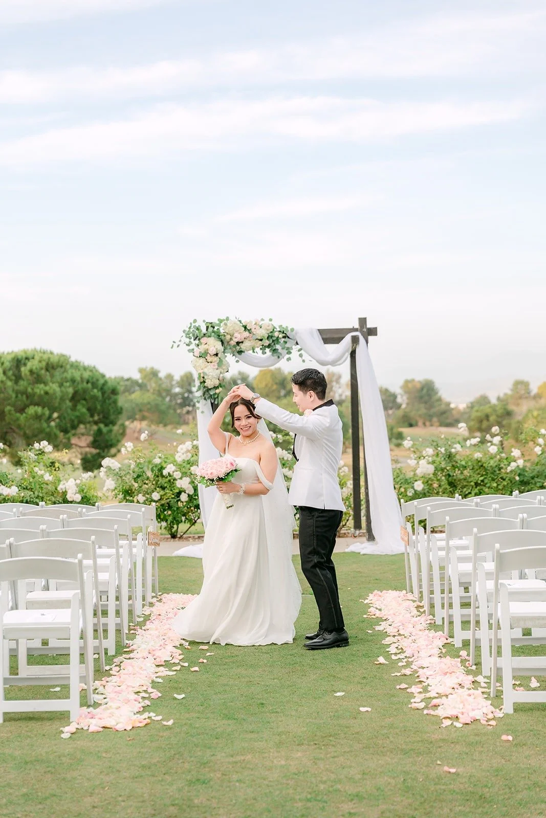 Ivy and Chungman at the end of the aisle lined with pink petals