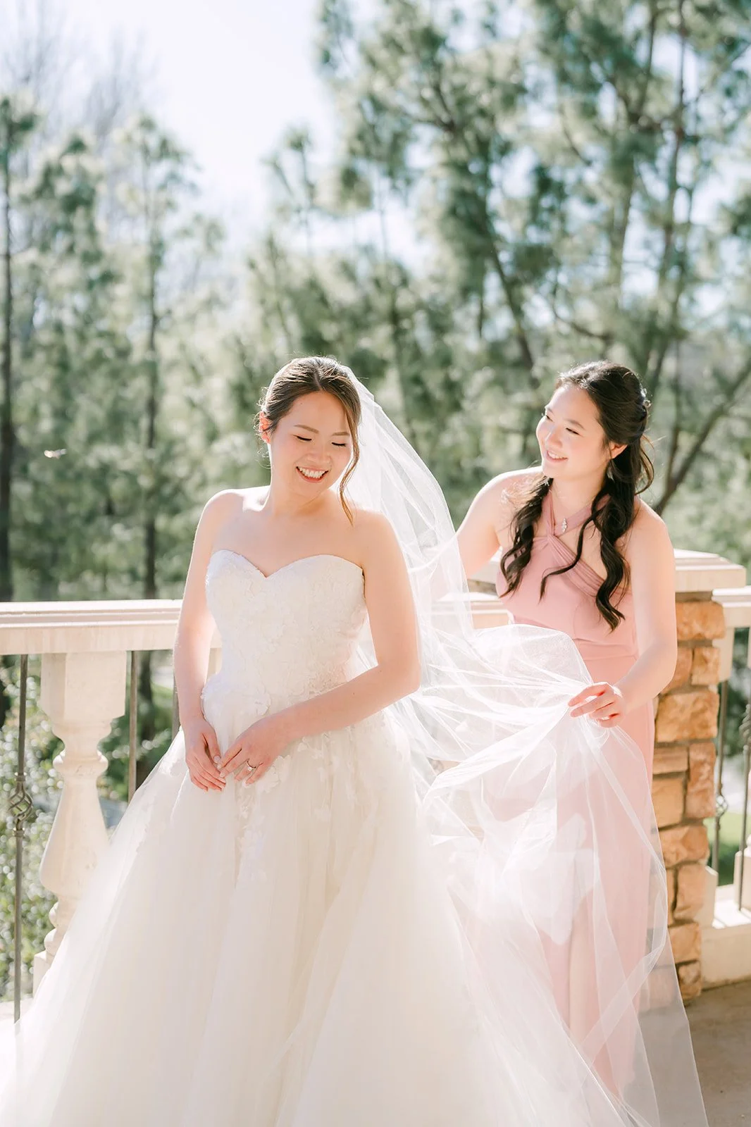 Bride in a strapless gown with her maid of honor on the balcony