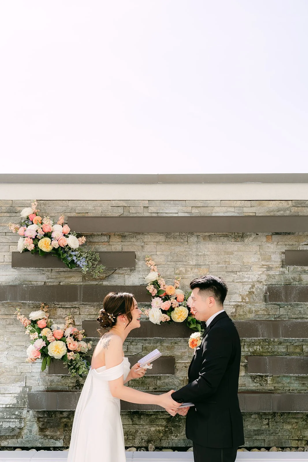 Amanda and San facing each other in front of the stone wall.