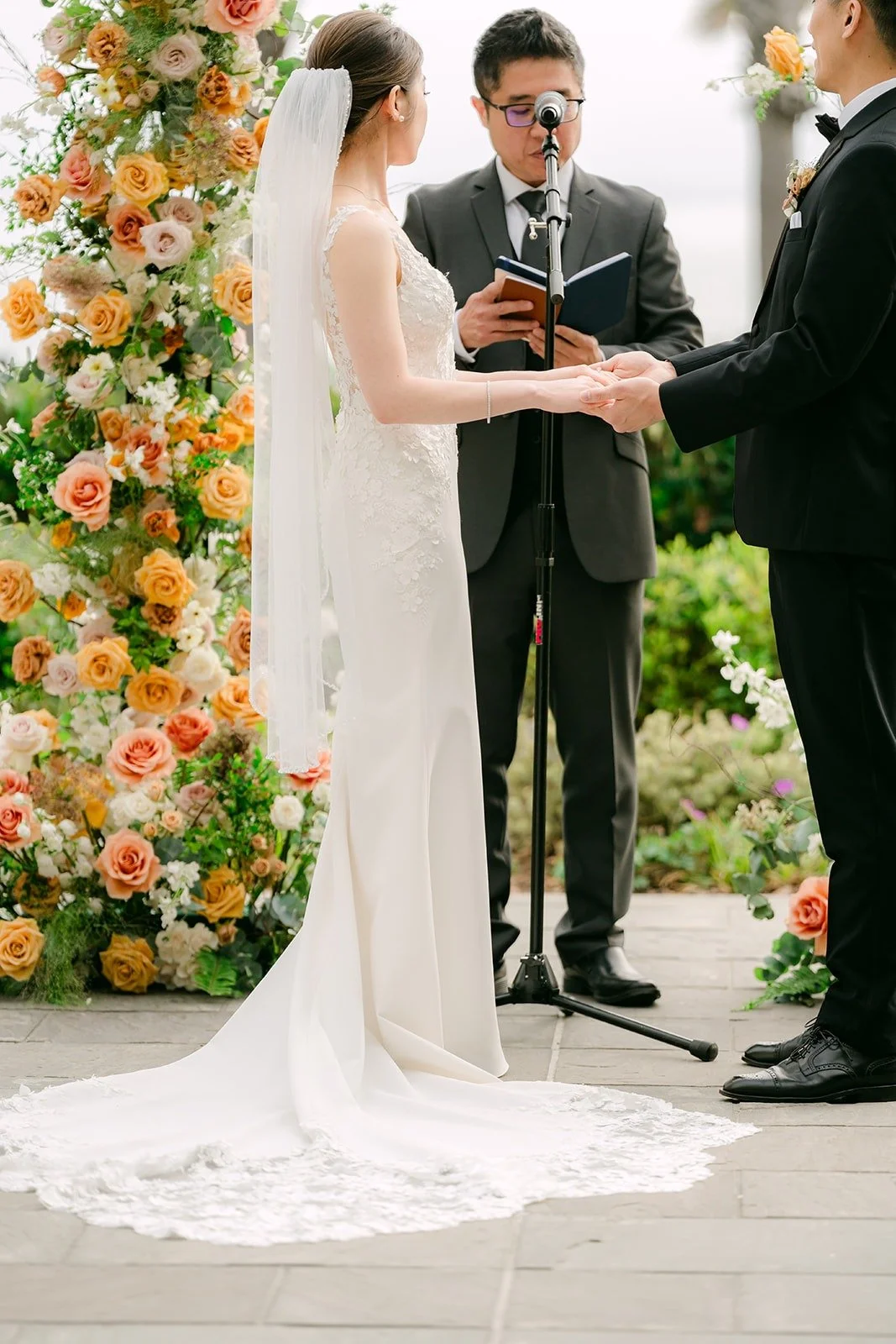 Angela and Eli exchanging rings with the officiant between them