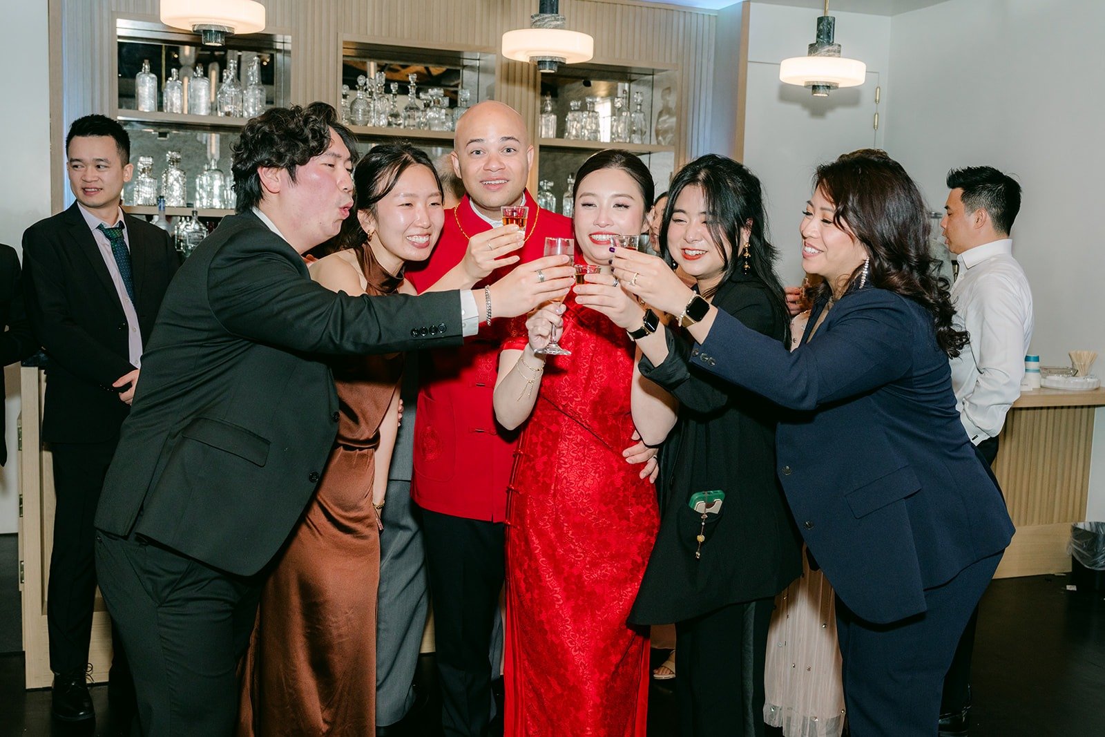 Elisa and Brandon toast with guests by the bar