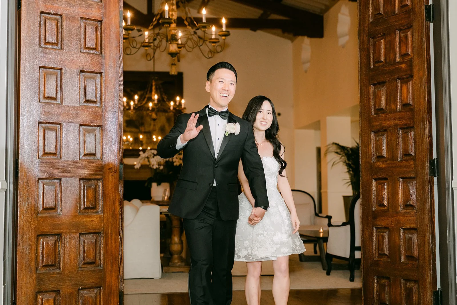 Newlyweds making their grand entrance through carved wooden doors