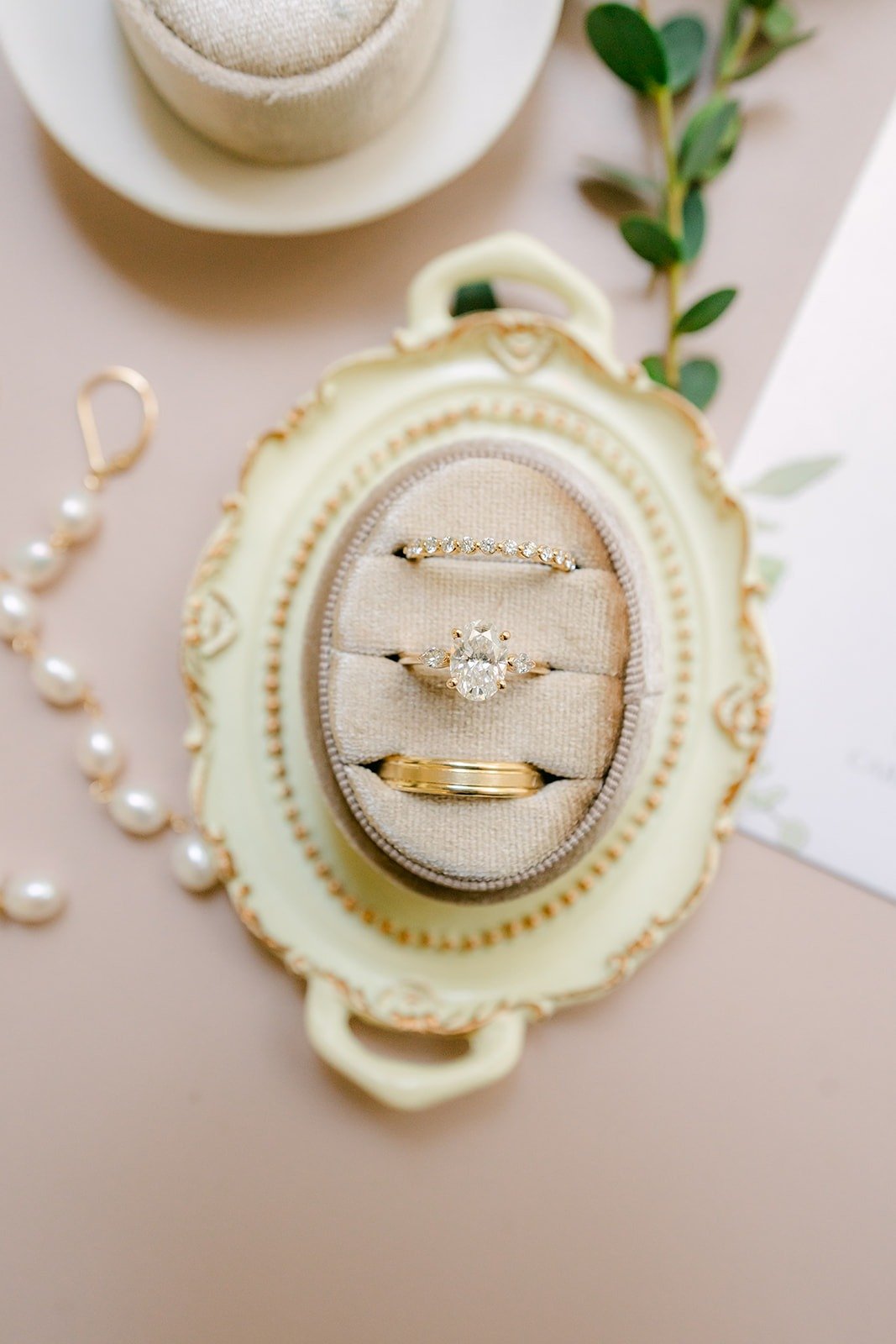 Wedding rings in an ornate cream ring box with a strand of pearls