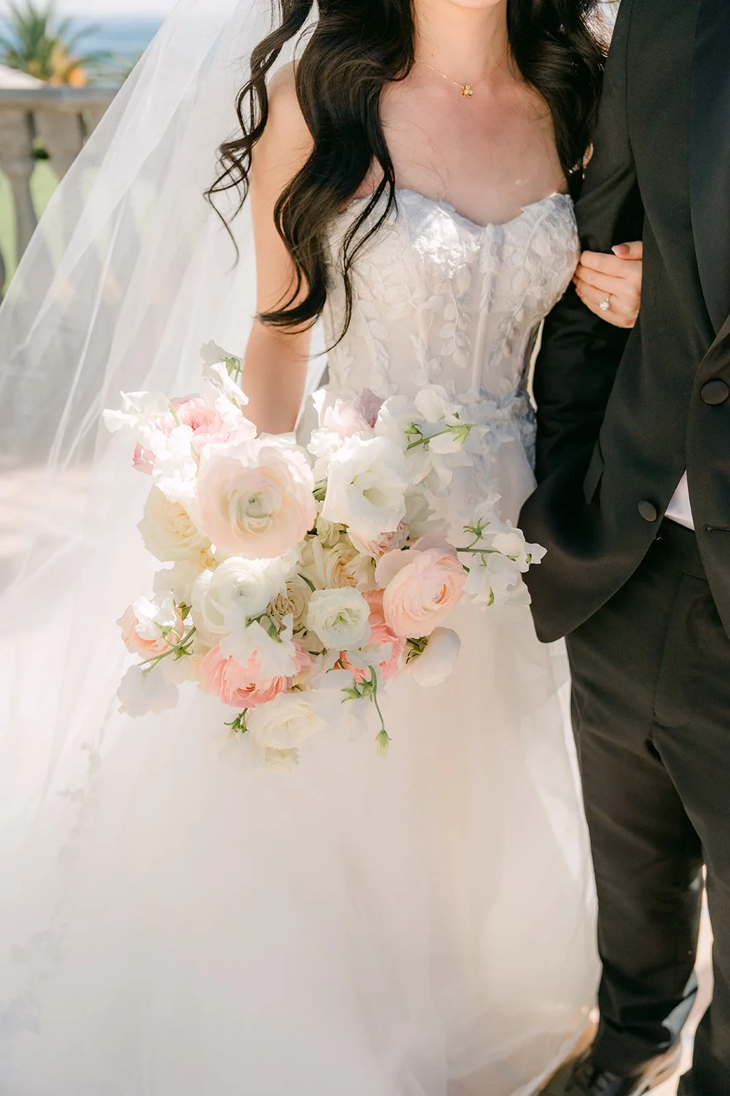Bride with a blush and ivory bouquet holding the groom's arm