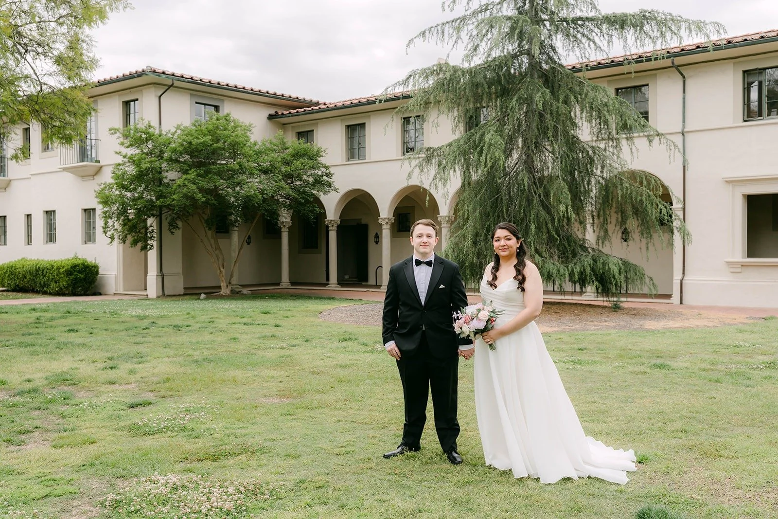 Saira and Matthew standing together on the lawn in front of The Athenaeum