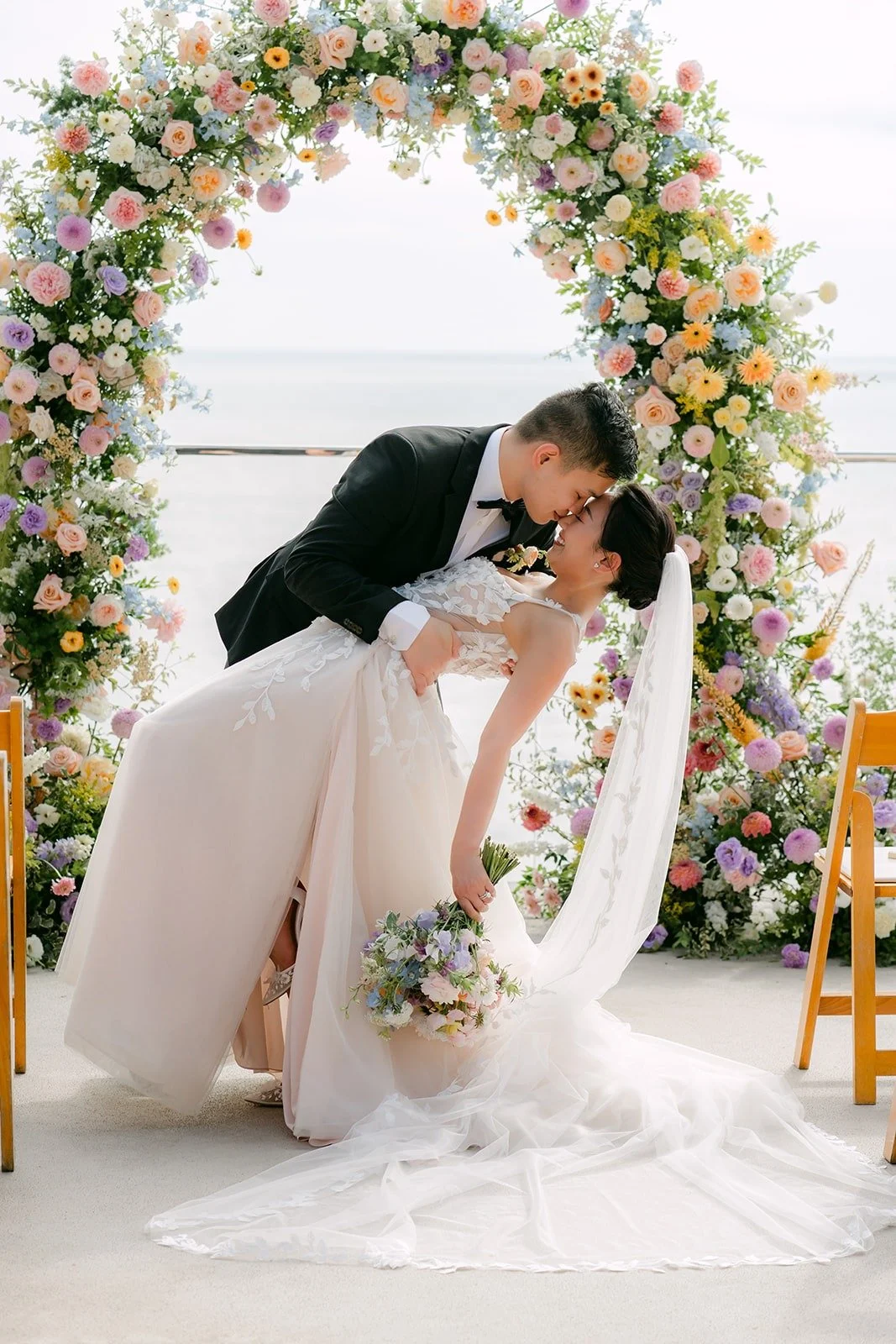 Mario dipping Kylie for a kiss under the floral arch