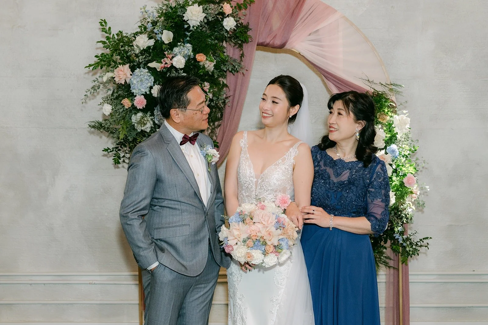 Elisa and Brandon with two family members at the floral arch