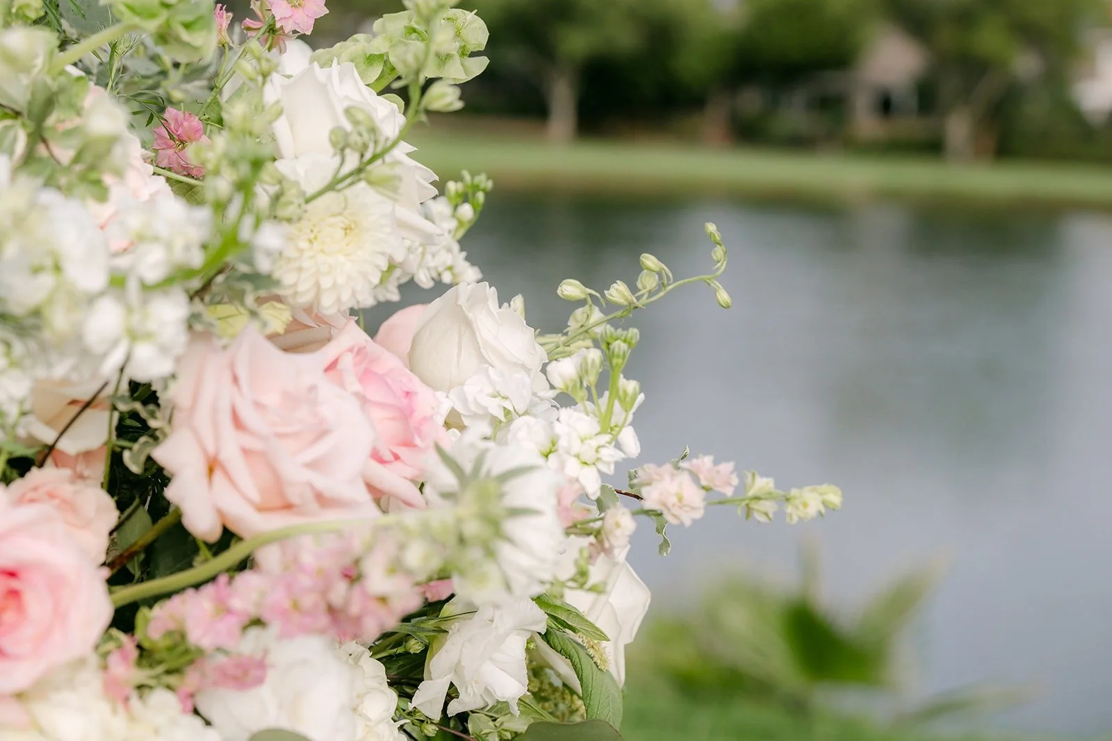 Pink roses framing the lake beside the ceremony lawn, photographed by One and Only Production