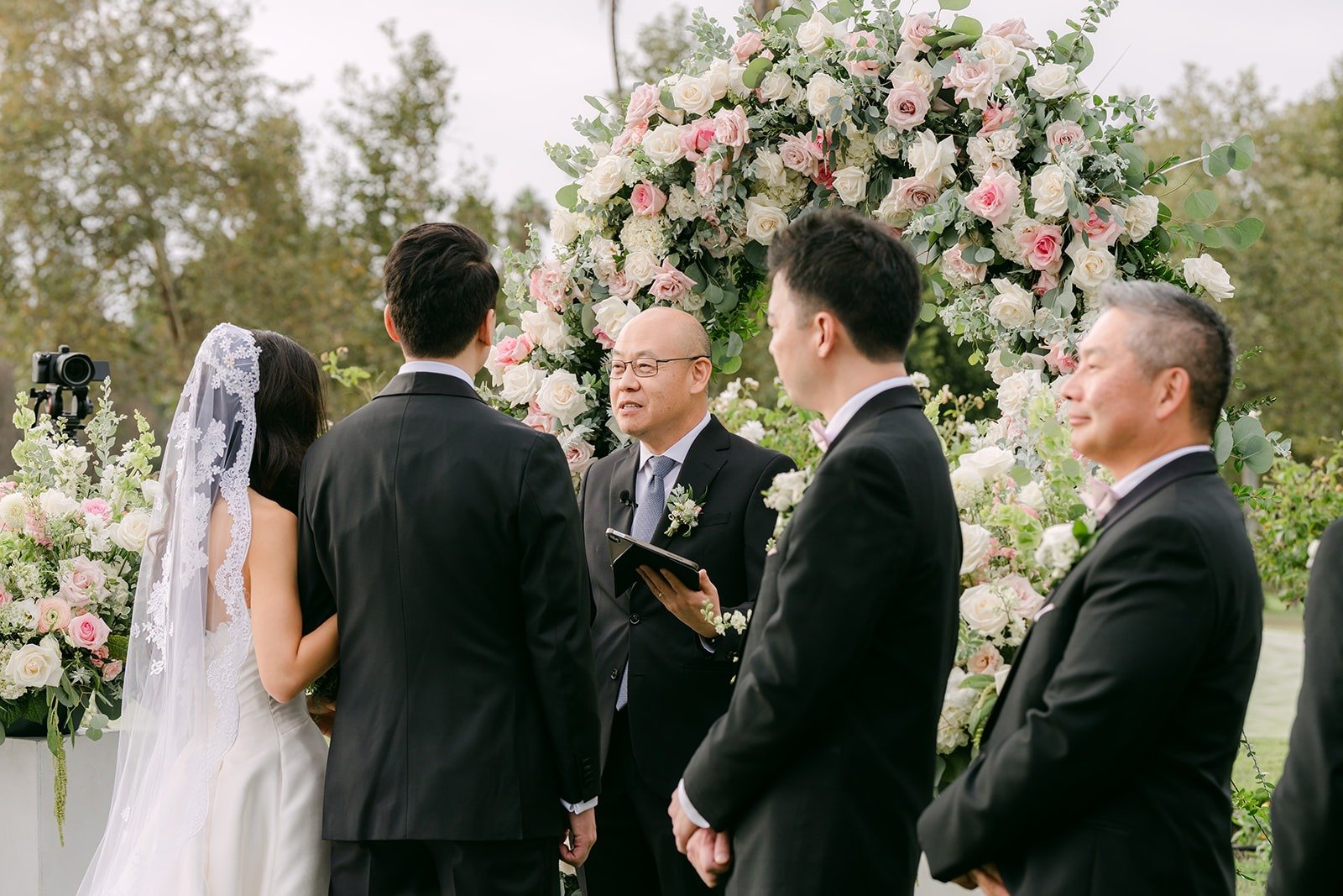 Kristine and William under the arch with the groomsmen beside them