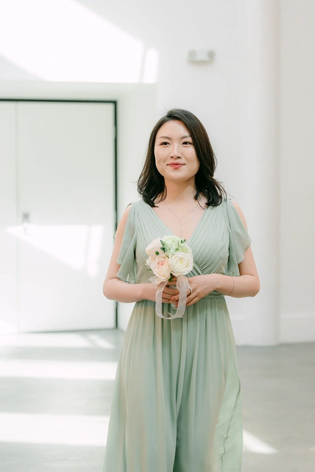 A bridesmaid in sage green walking down the aisle