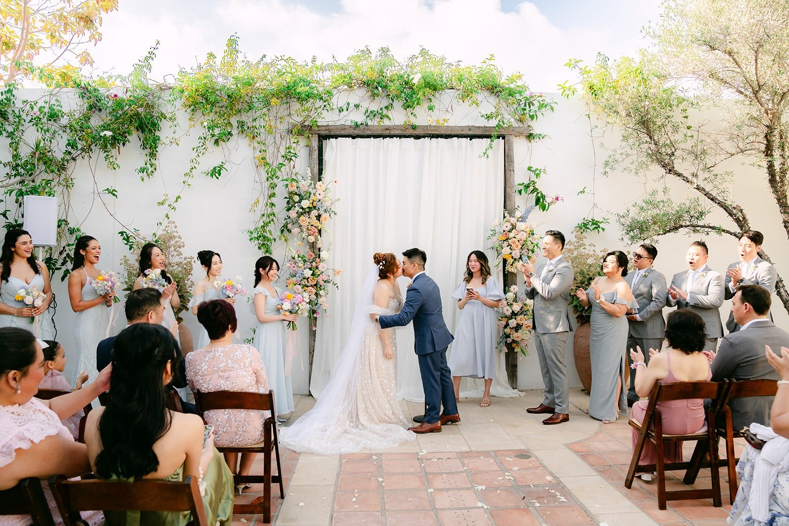 Wide view of the ceremony in the courtyard with guests on both sides of the aisle