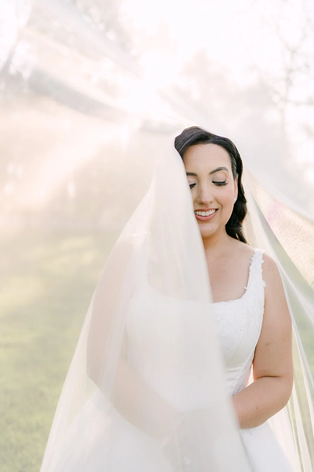 Bride smiling under her veil in golden afternoon light