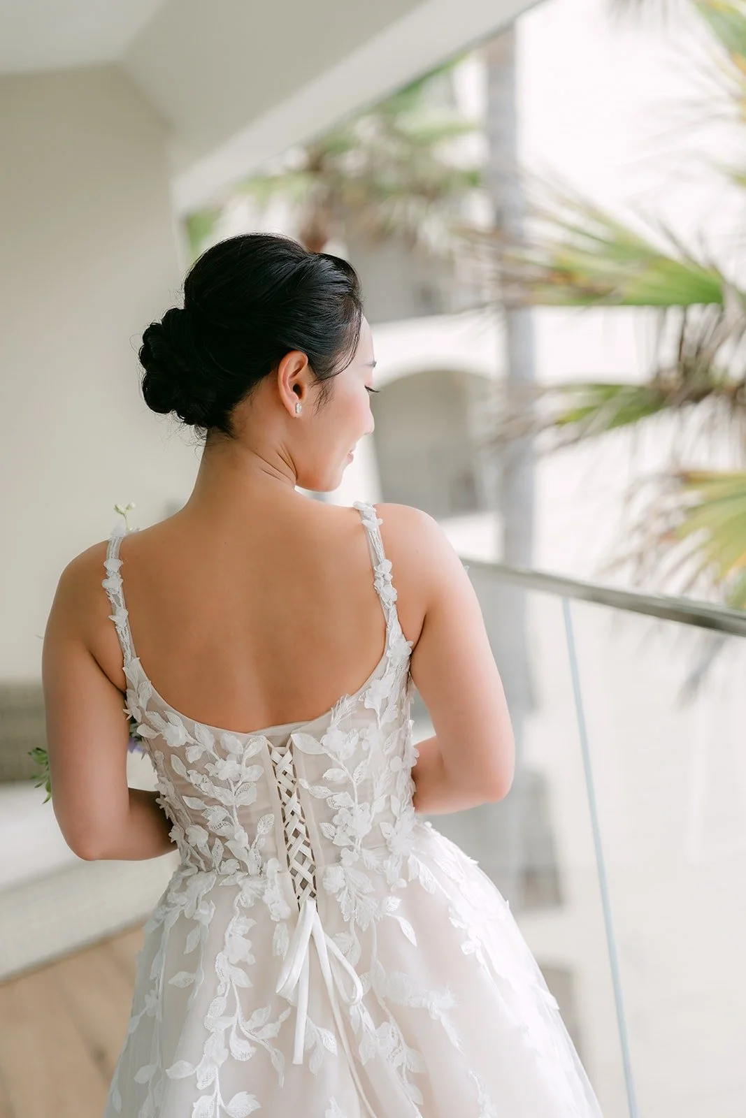 The lace up back of Kylie's gown against the palms outside